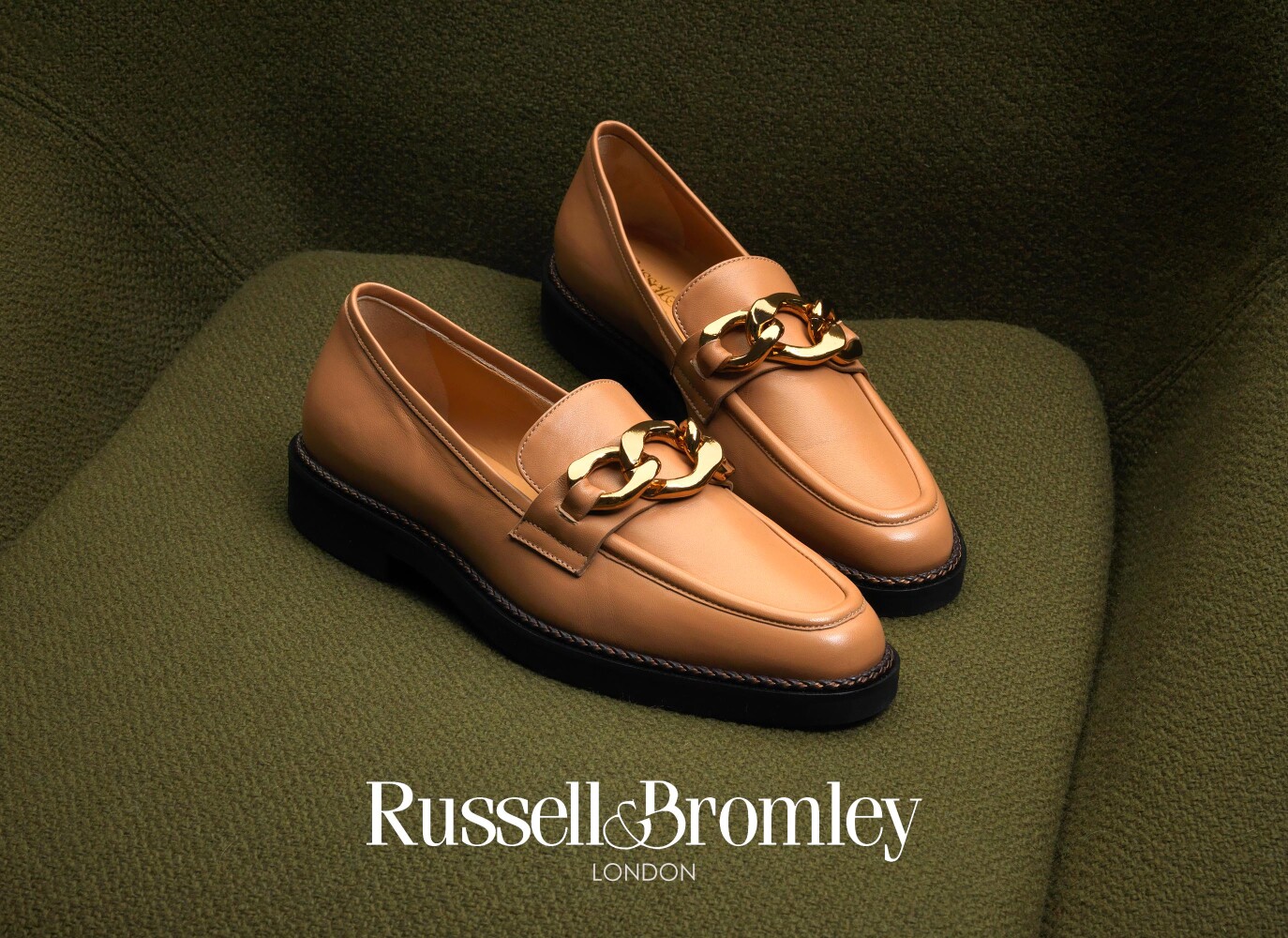 Russell & Bromley tan leather loafers with gold chain detail — luxury footwear product still life photography by Leo Acker, London, styled on green bouclé fabric Leo Acker Photographer ADVERTISING 
